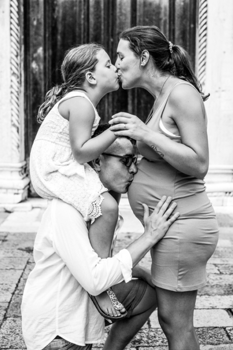 servizio fotografico venezia - gravidanza papà bacia la pancia con figlia sulle spalle