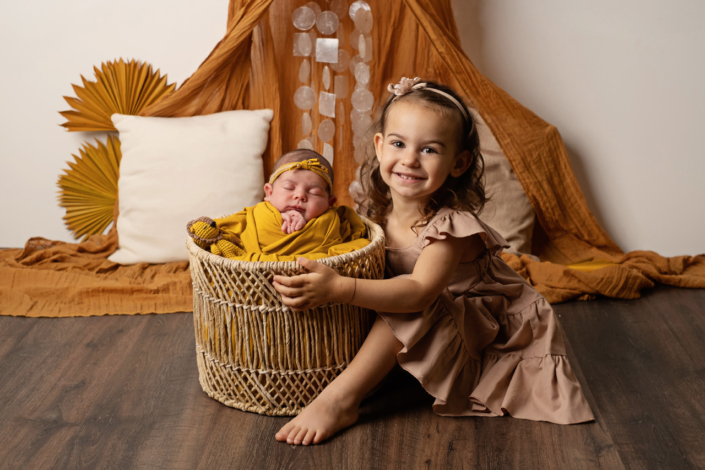 fotografo newborn venezia_ sorella maggiore con neonata nella cesta ocra