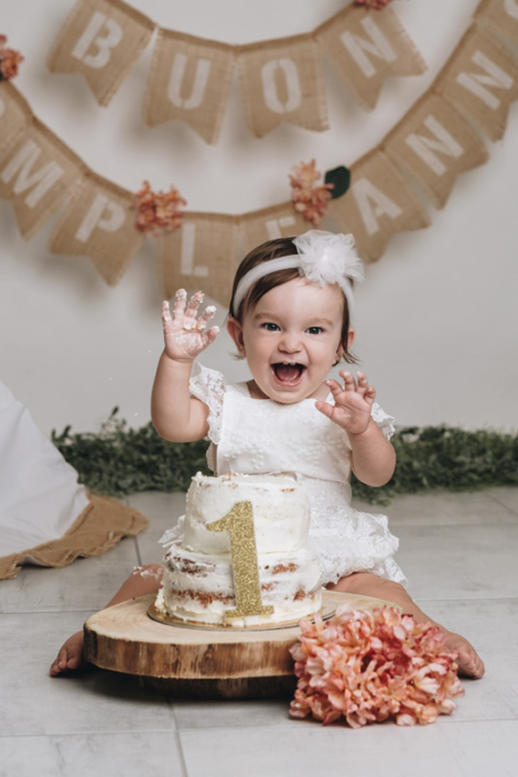 smash cake primo compleanno - bambina che ride dentro la torta