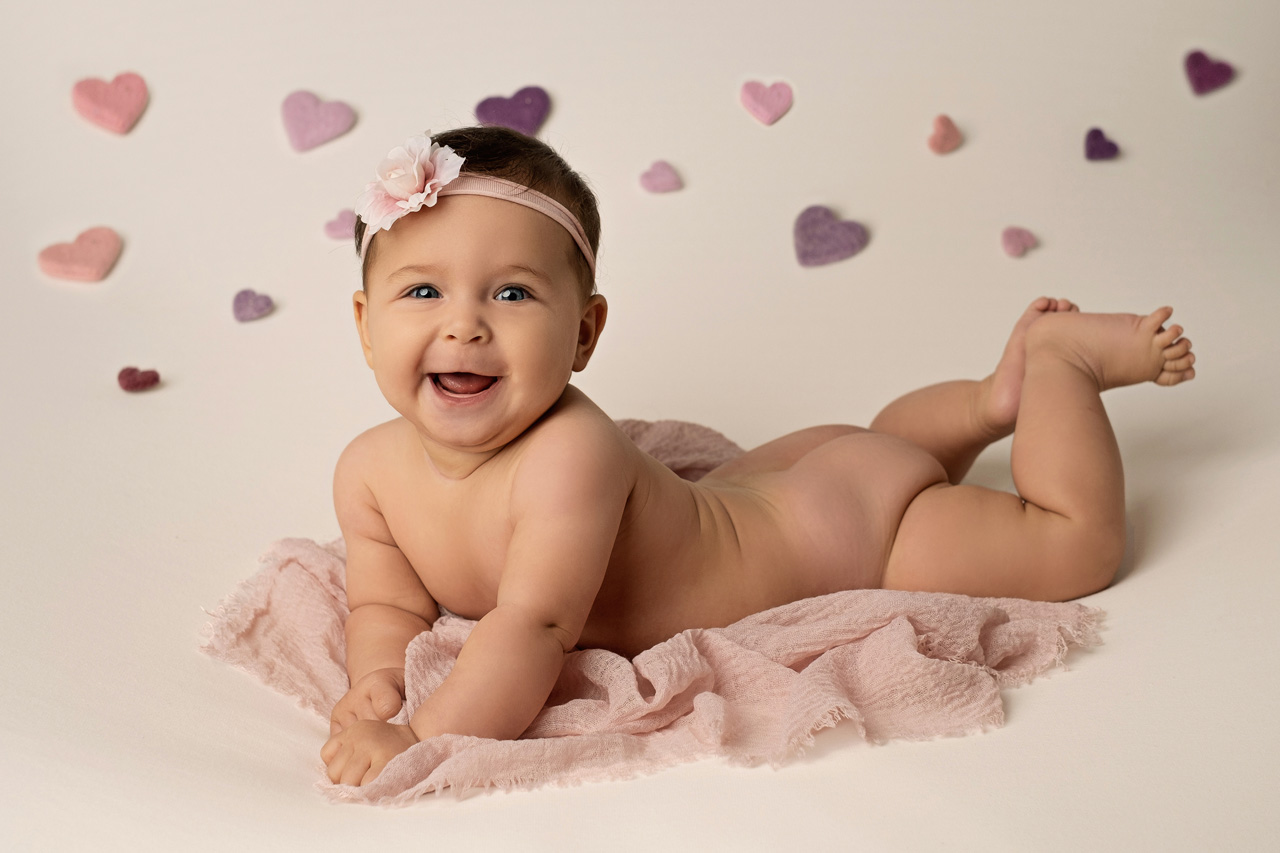 servizio fotografico bambini venezia con bambina di 7 mesi che sorride con cuoricini sullo sfondo